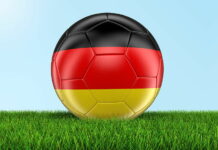 football painted with germany flag close up on grass sky background