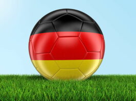 football painted with germany flag close up on grass sky background