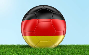 football painted with germany flag close up on grass sky background