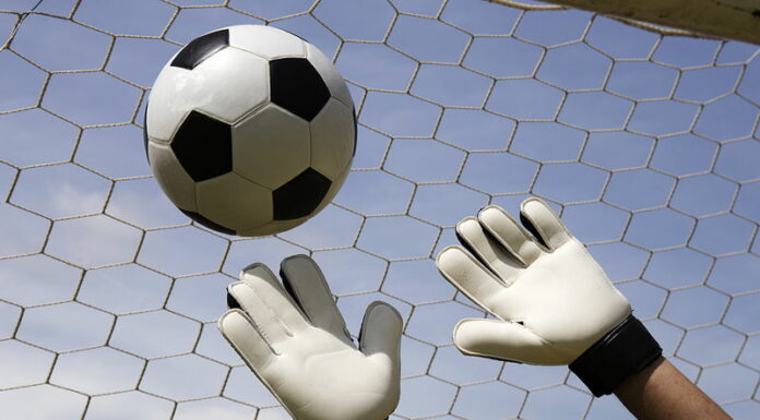 goalkeeper trying to make a save ball just out of reach going into the top corner of the goal