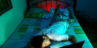 man lying in bed asleep laptop still running playing game late into the night