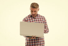 casual man playing football manager on a laptop